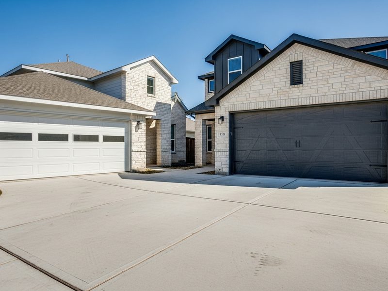 Two neighboring Frisco TX homes with white steel and dark faux wood garage doors